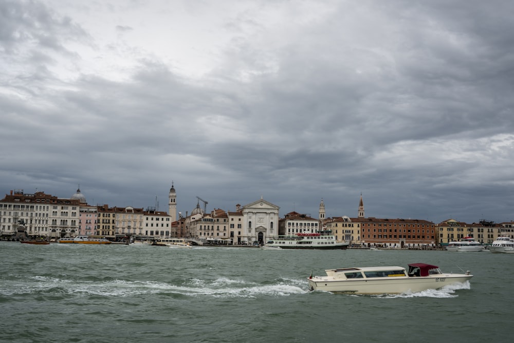 a white boat traveling down a river next to tall buildings