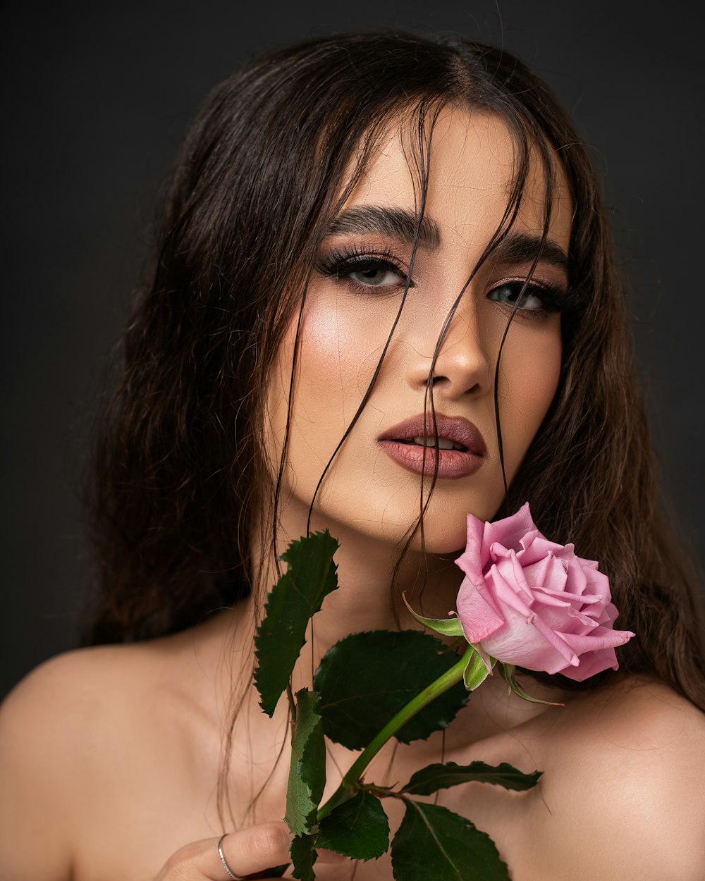 a woman holding a pink rose in her hand