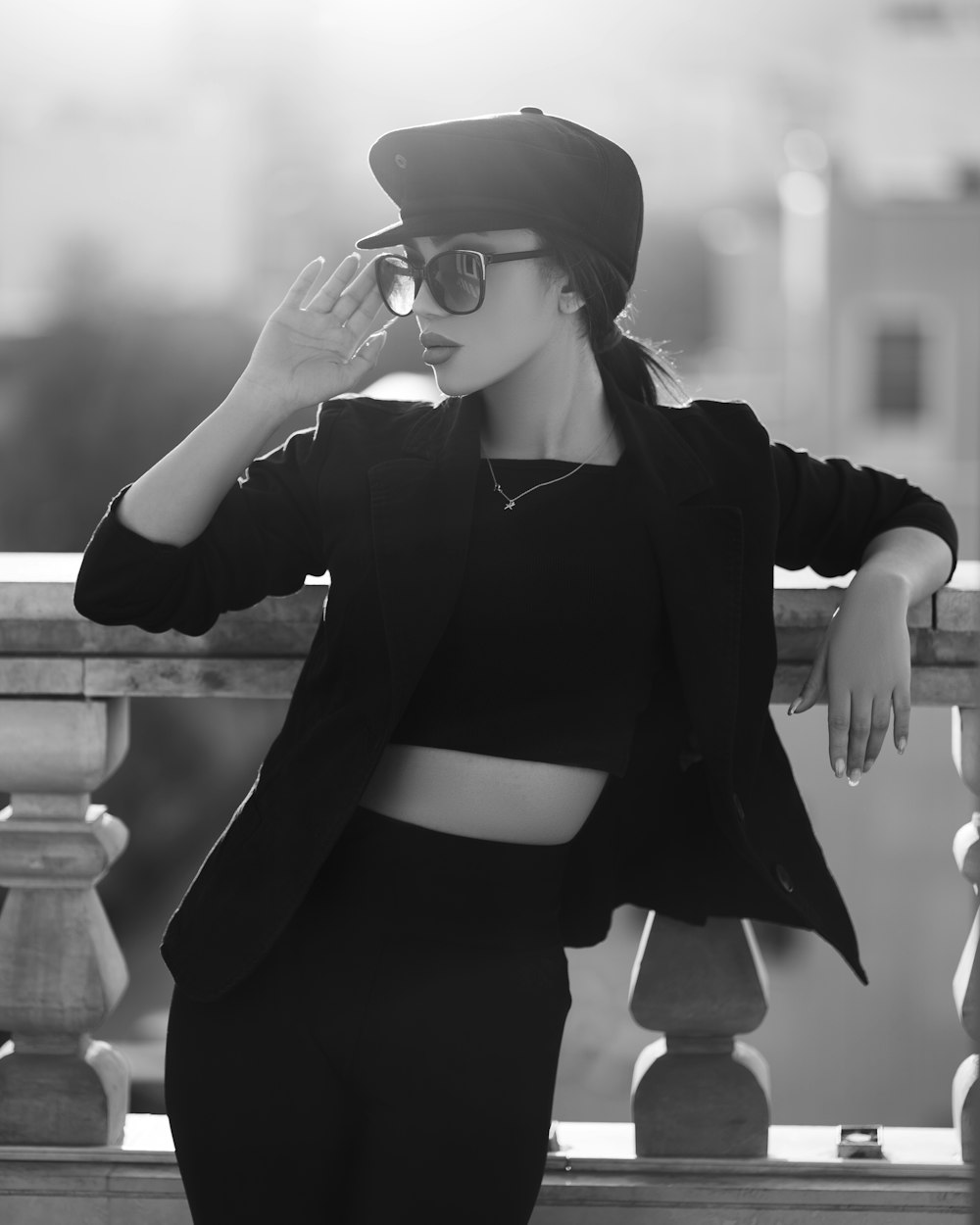 a woman wearing a hat and sunglasses leaning on a railing