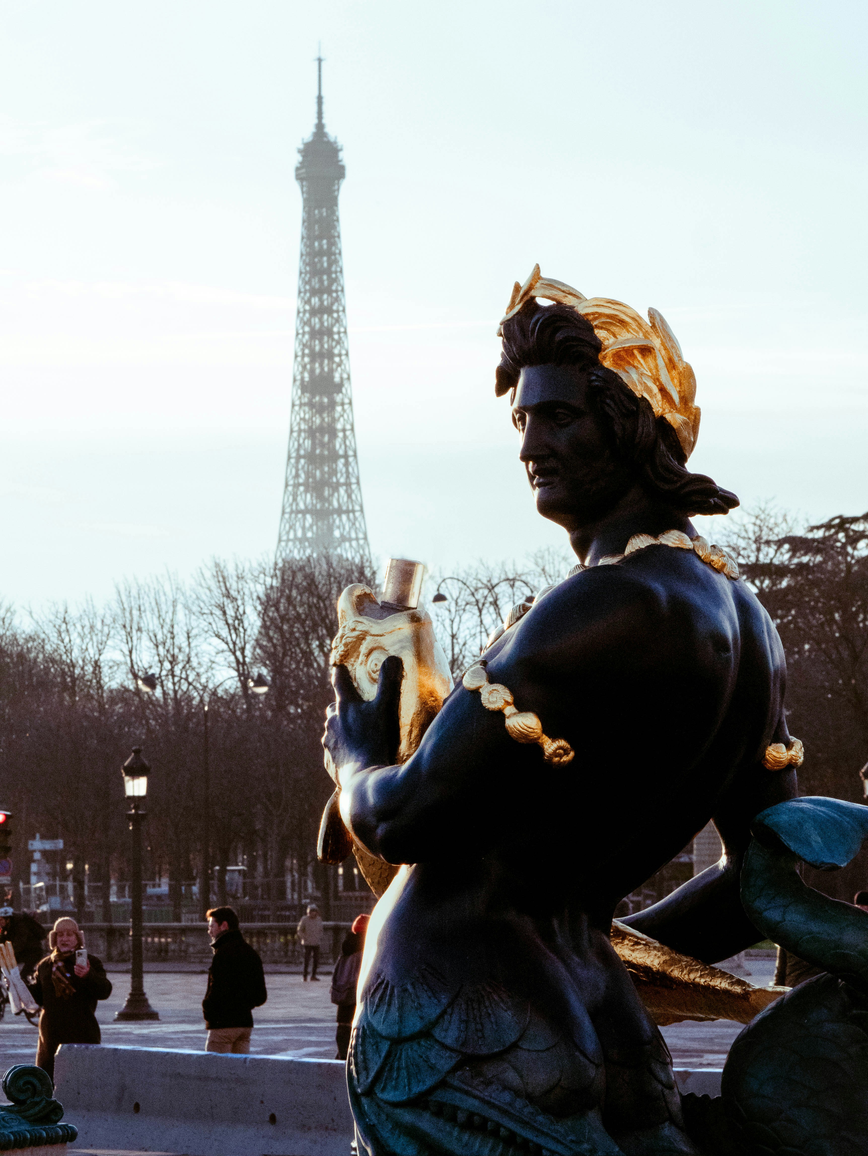 Una statua di una donna che tiene in braccio un gatto di fronte alla Torre Eiffel