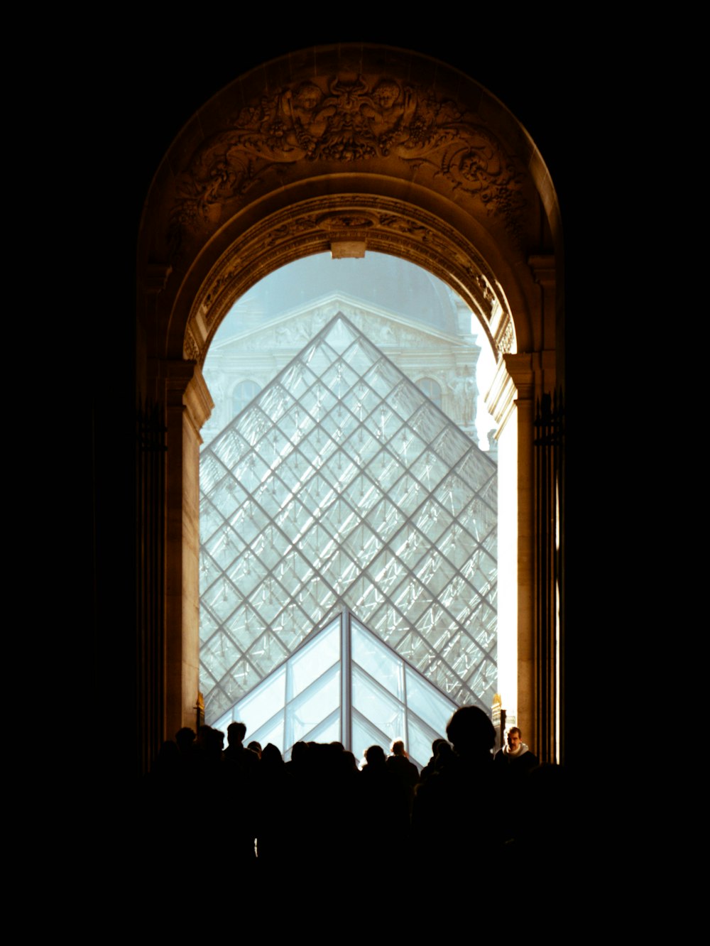 a group of people standing in front of a glass pyramid