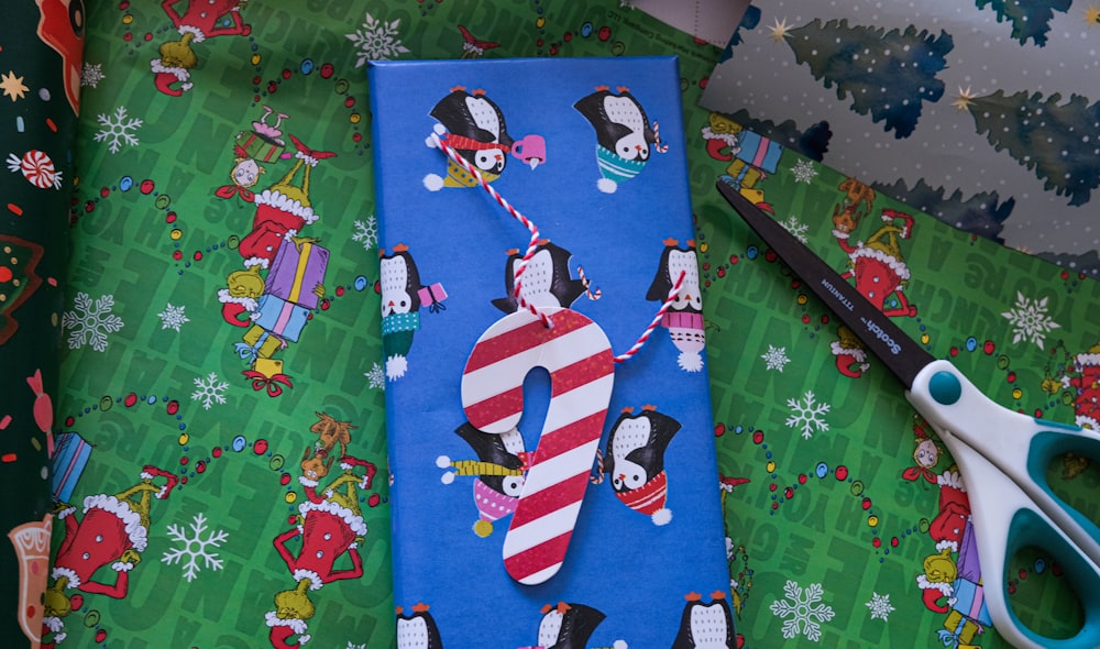 a pair of scissors sitting on top of a christmas wrapping paper