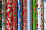 A festive display of gift bags and wrapping paper rolls in bright, cheerful colors.
