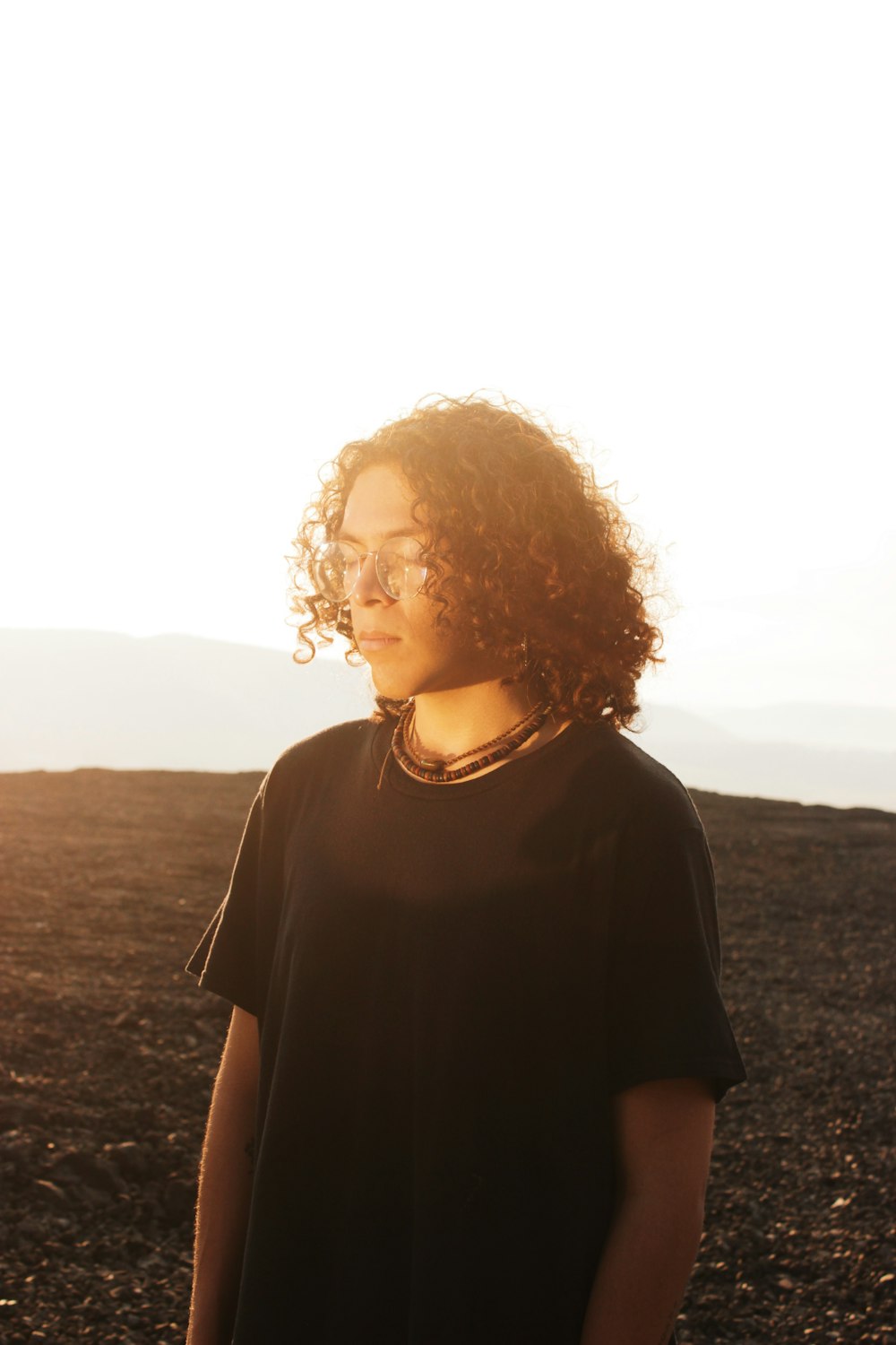 a woman with curly hair standing in a field