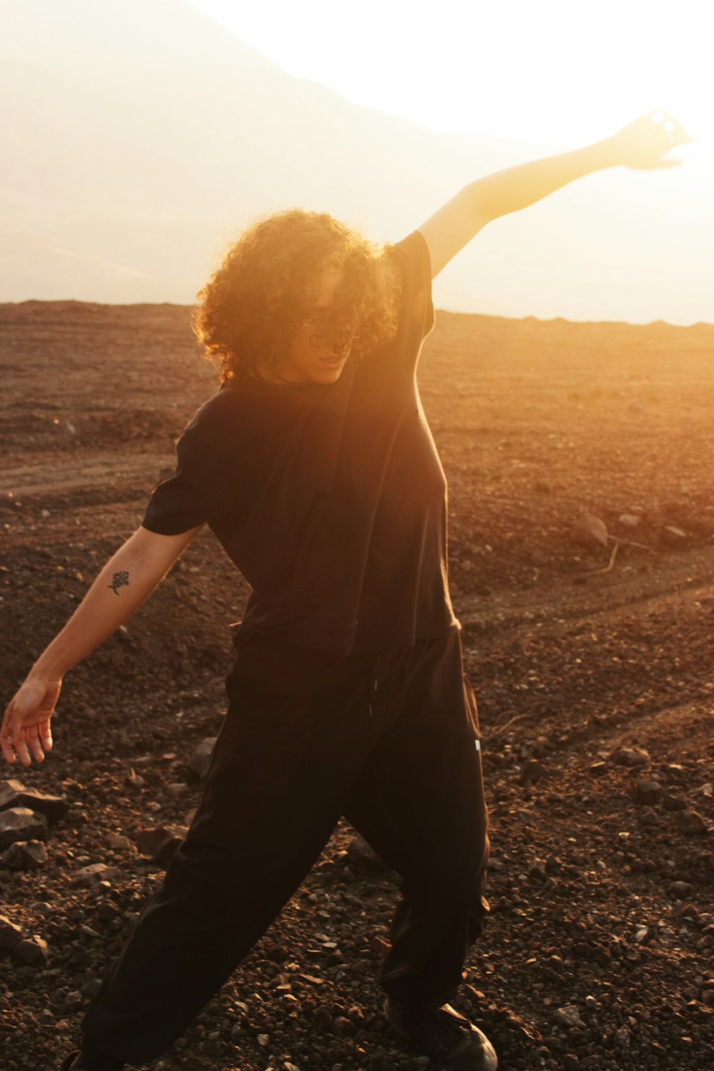 a man standing in the middle of a dirt field