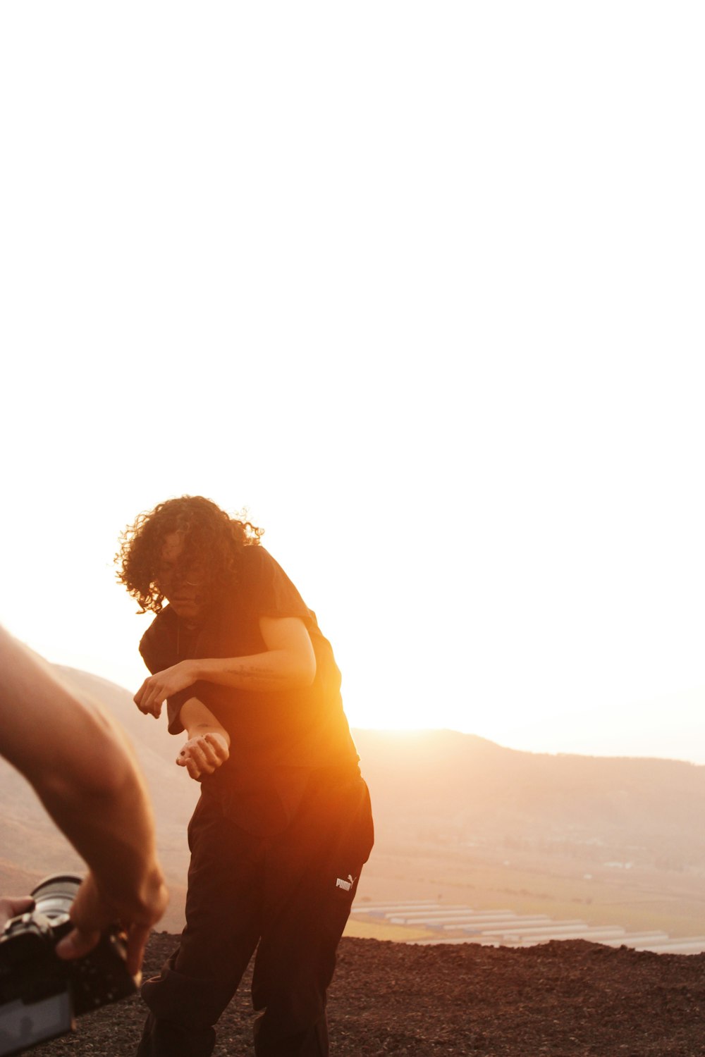 a woman standing on top of a hill next to a suitcase