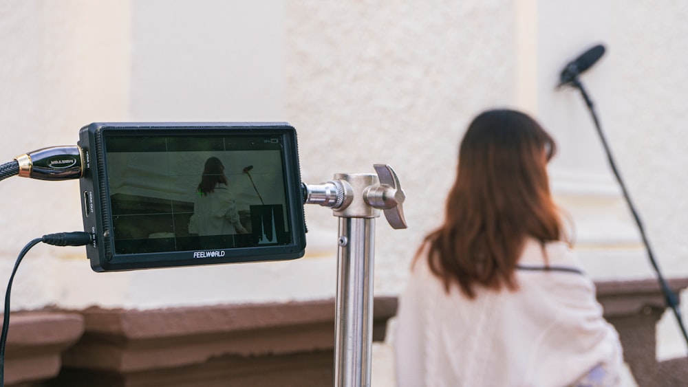 a woman standing next to a pole with a camera on it