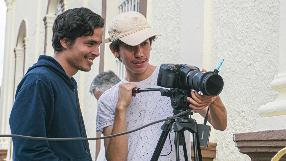 a couple of men standing next to a camera