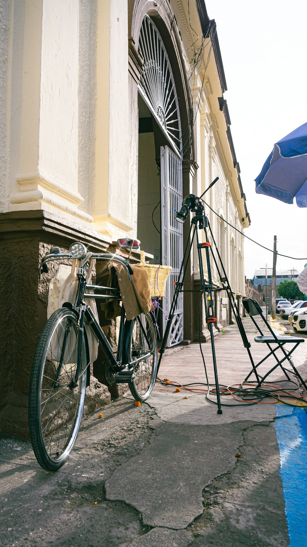 a bicycle parked outside of a building next to a blue umbrella
