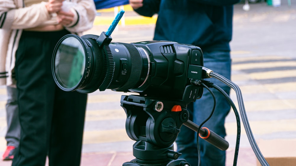 a camera on a tripod with people standing around