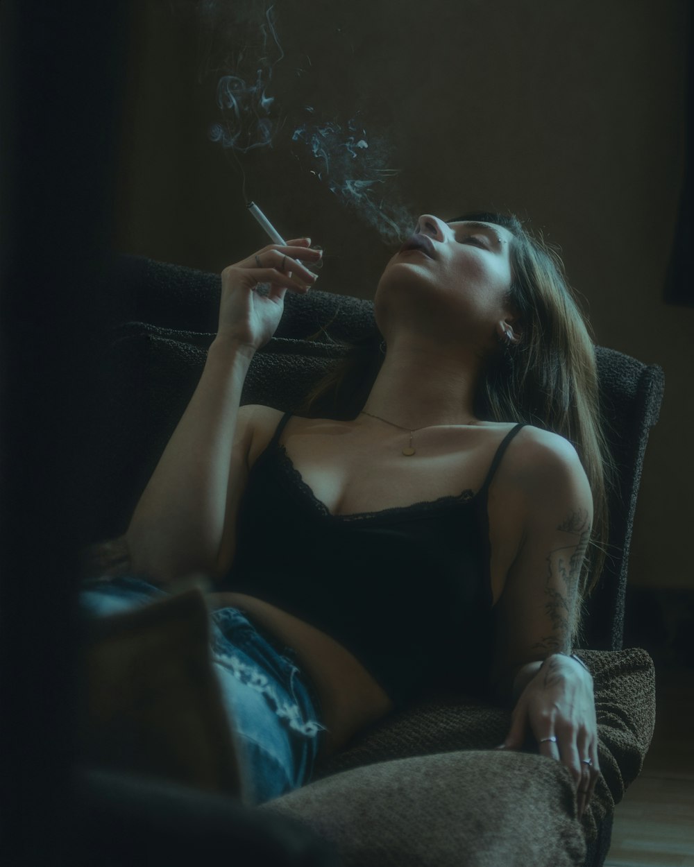 a woman sitting on a couch smoking a cigarette