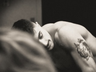 Black and gray tattoo of a wolf howling at the moon on upper arm.