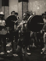 Trainer demonstrating proper lifting technique to a focused football player.