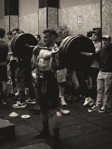 High-contrast editorial photo of a focused male athlete lifting weights in a gritty gym environment.