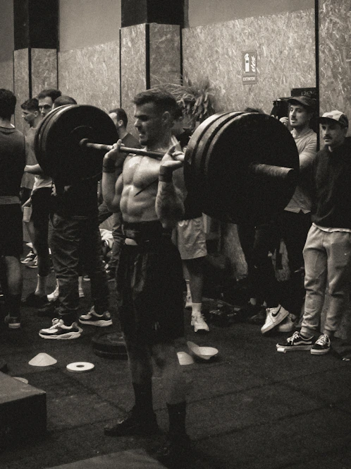 High-contrast editorial photo of a focused male athlete lifting weights in a gritty gym environment.