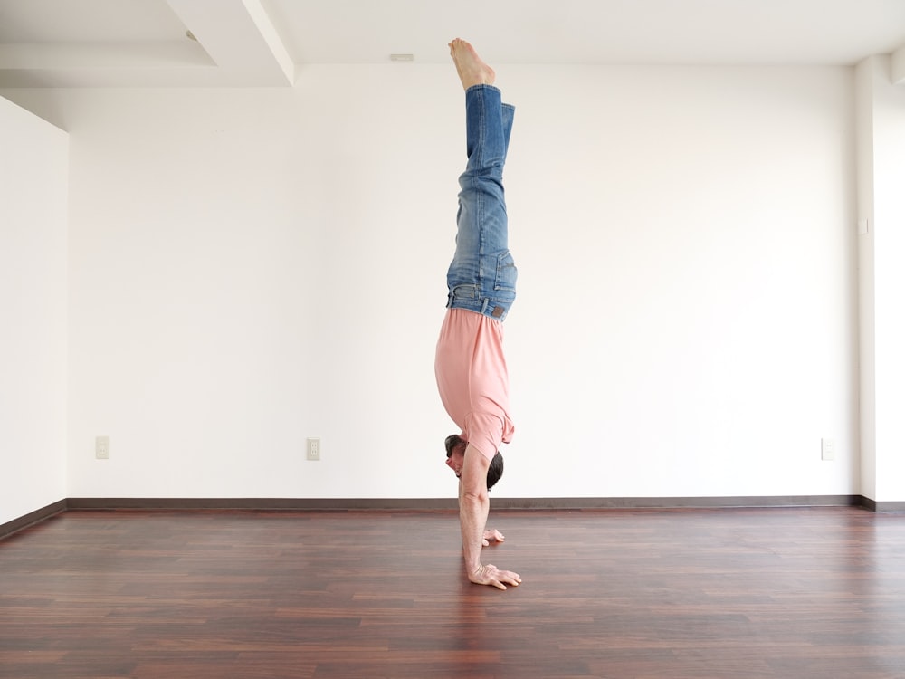 a person doing a handstand on a wooden floor