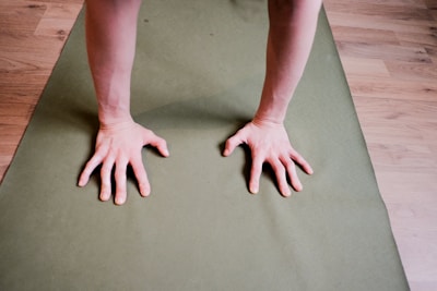 Close-up of hands and feet during a Pilates exercise on a mat with natural light.