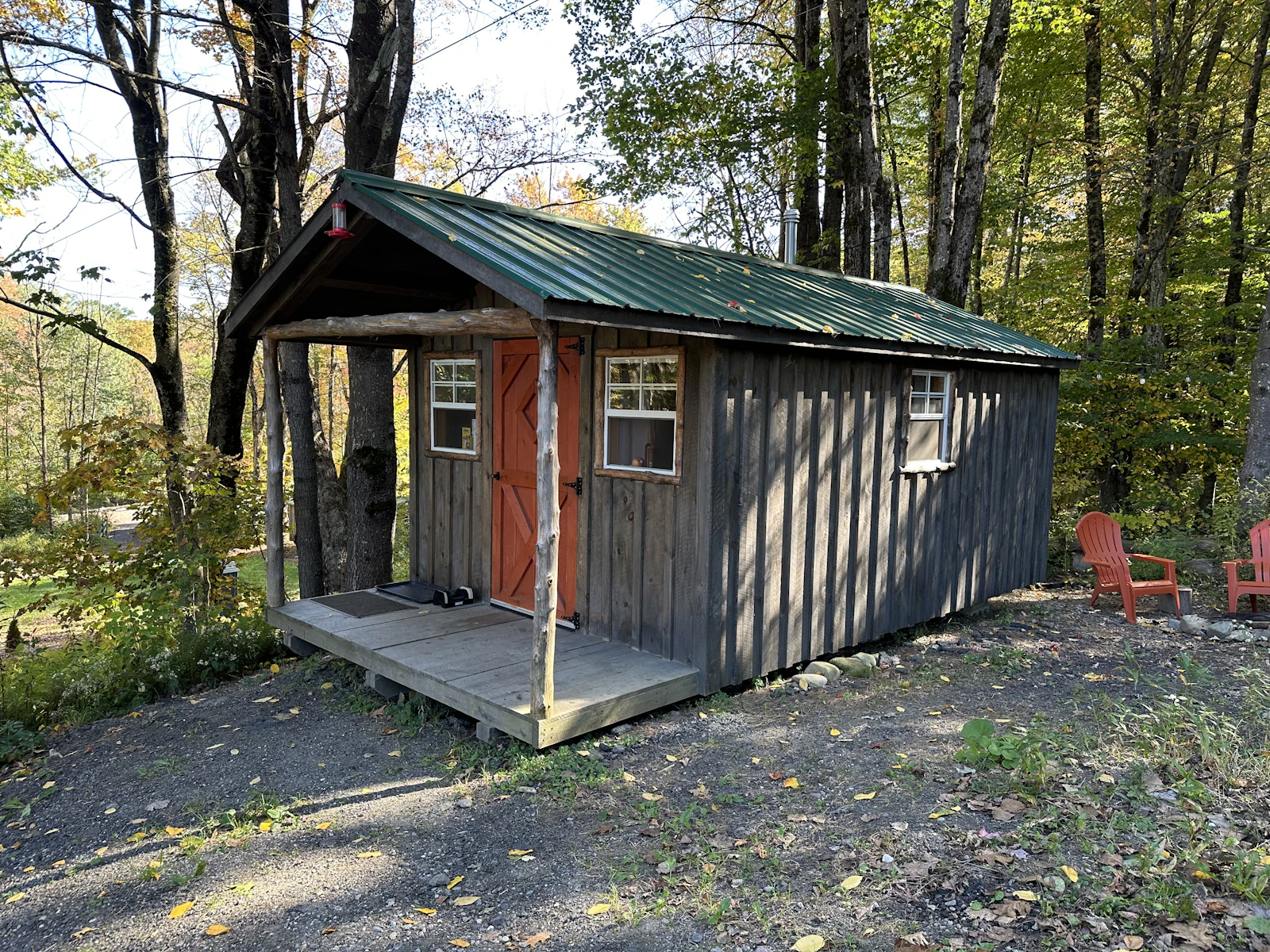 A small off-grid cabin in a wooded setting. Every subsystem visible here — power, water, waste — answers to its own standard; there is no single "off-grid code" that covers all three at once.