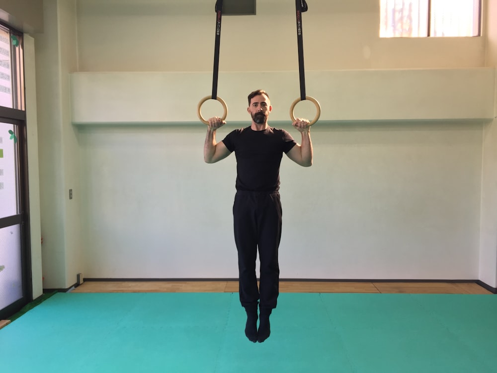 a man is doing a pull up exercise with two rings