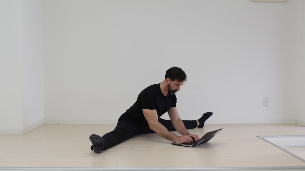 Un hombre sentado en el suelo usando una computadora portátil