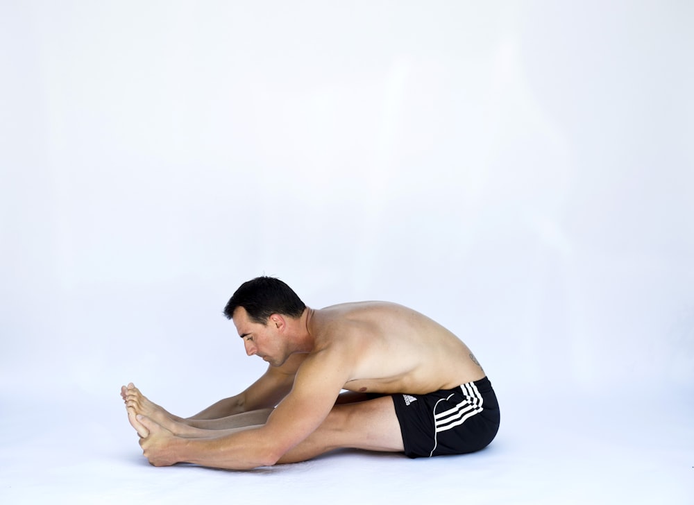 a shirtless man sitting on the ground with his legs crossed