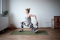 A teen smiling while stretching on a soft yoga mat, surrounded by plants.