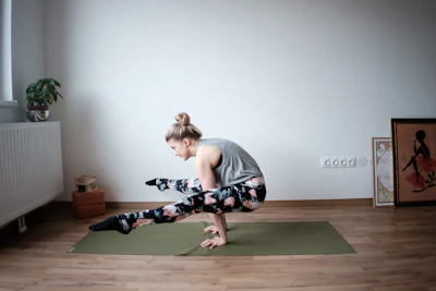 Yoga enthusiast stretching on a mat in a sunlit studio with minimalistic decor.