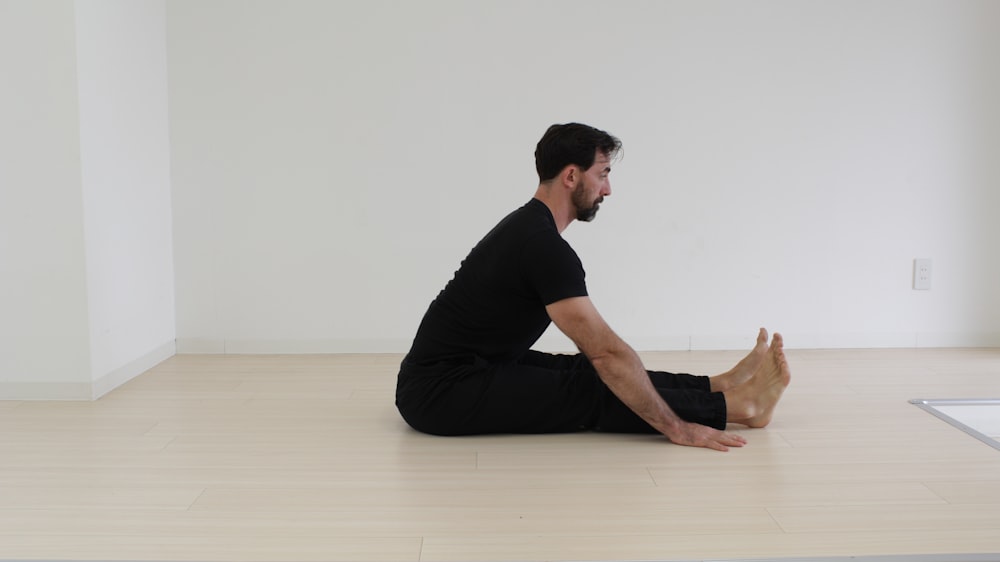 a man sitting on the floor in a white room