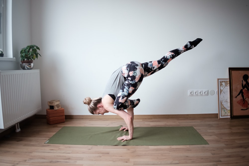 a woman doing a handstand on a yoga mat