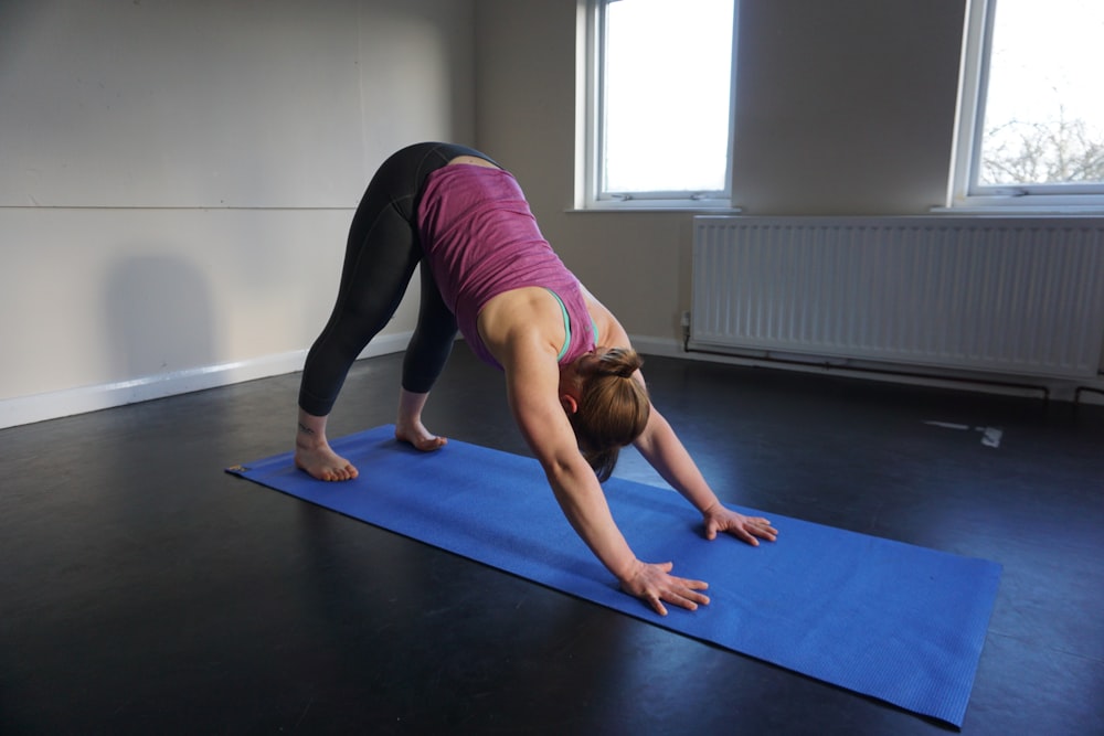 a woman doing a yoga pose on a blue mat