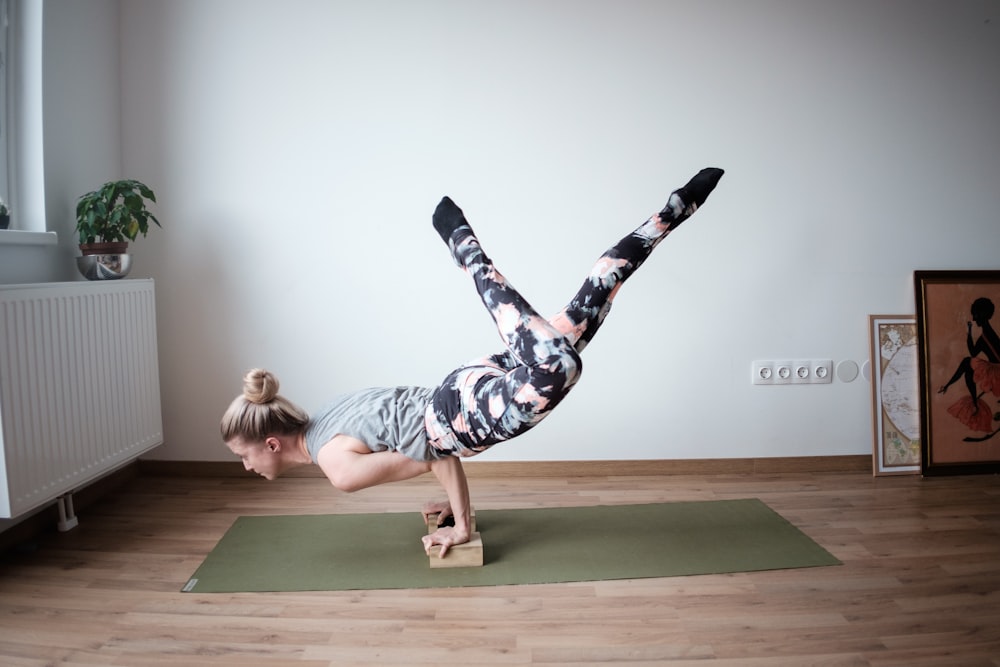 a woman doing a handstand on a yoga mat