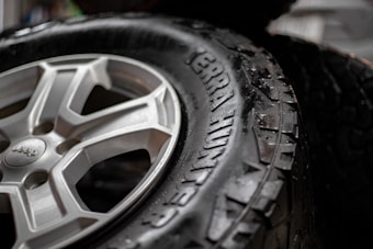A close-up view of a black tire with visible tread patterns. The tire is labeled 'Terra Hunter' and appears wet, suggesting recent contact with water. Beside the tire is a metallic wheel with a detailed design, exhibiting a silver color.