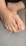 A close-up view of a foot resting on a gray fabric surface, showing detailed skin texture and nail features.