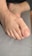 A close-up view of a foot resting on a gray fabric surface, showing detailed skin texture and nail features.