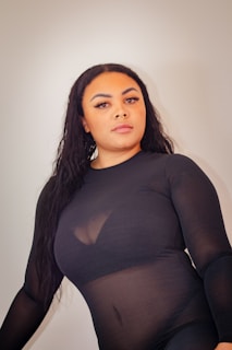 Model wearing a black outfit blending into a transparent, glossy background