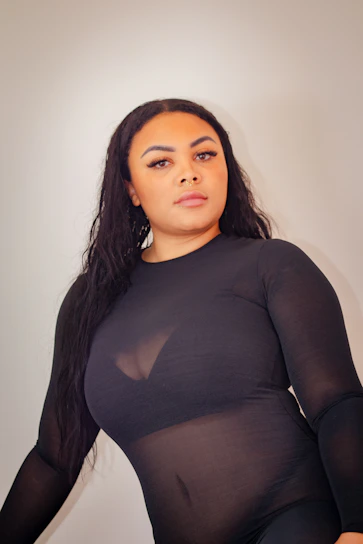 A sleek, minimalist photo of a model wearing a sharp, modern outfit from Elite Frieza Clothing, set against a neutral urban backdrop.