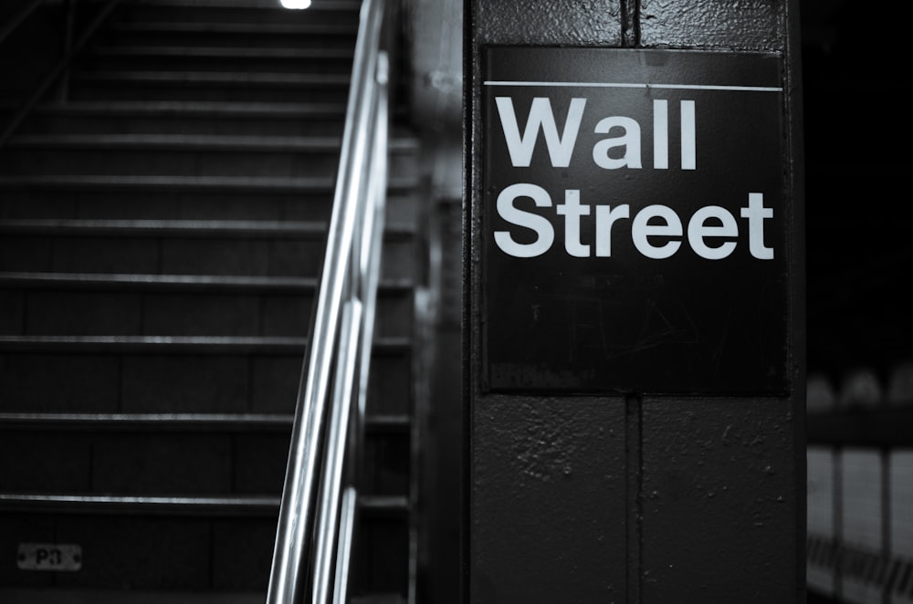 a black and white photo of a wall street sign