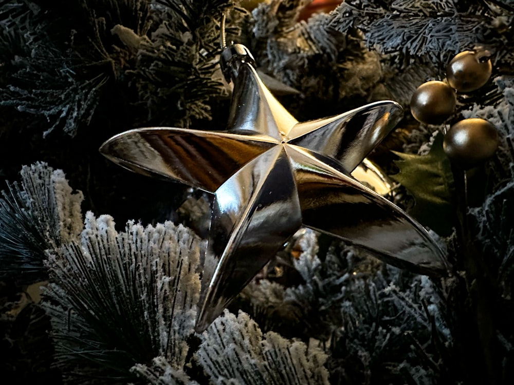 Un adorno de estrella plateada sentado en la parte superior de un árbol de Navidad