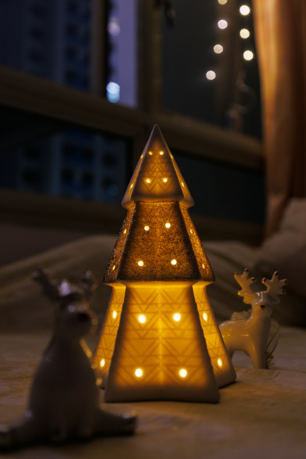 a lit up christmas tree sitting on top of a bed