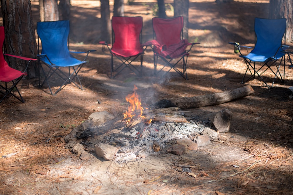 a campfire in the woods with chairs around it