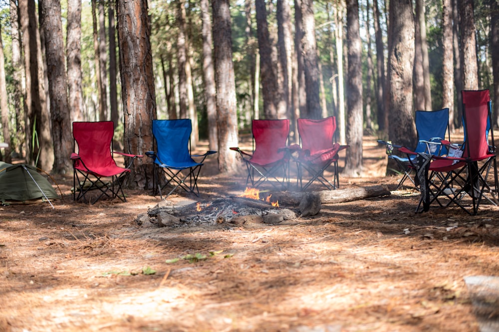 a group of chairs sitting around a campfire in the woods