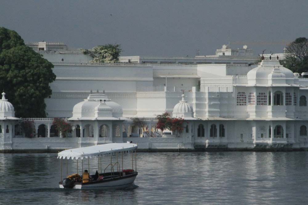 a boat is in the water in front of a white building