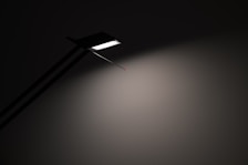 Sleek, minimal light fixture casting soft light over a clean bedside table.