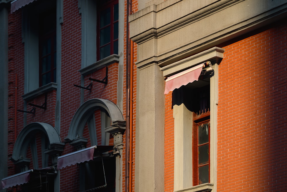 a brick building with an open window and a cat on the ledge