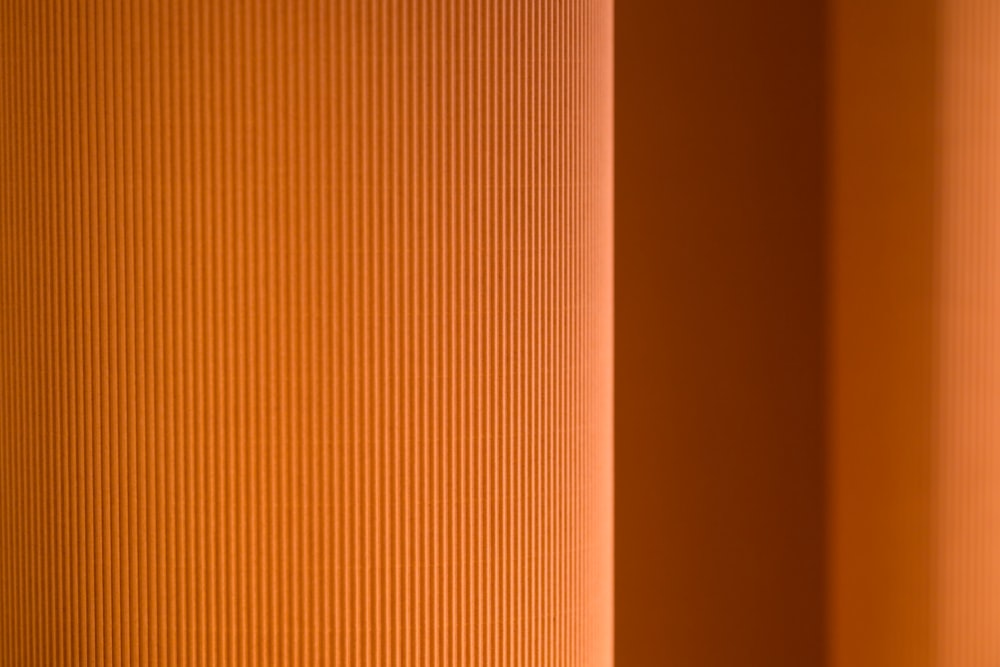 a close up of an orange wall with vertical blinds