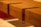 A close-up view of a wooden structure featuring a notched corner design with smooth finishes. The wood grain is visible, and the piece is positioned on a red support, which adds a modern accent to the overall look.
