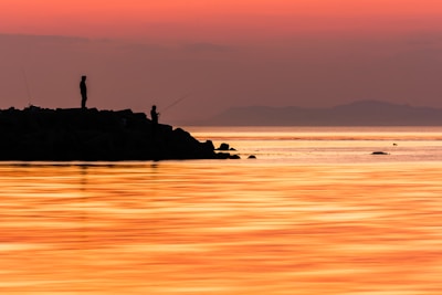 Sunset view over the sea with silhouettes of fishermen at work