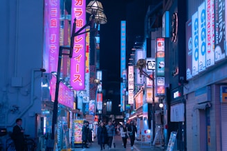 A vibrant street scene in Tokyo illuminated by colorful neon signs at night.