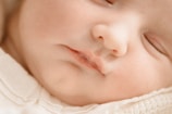 Close-up of a baby’s peaceful face, emphasizing natural textures and tones.