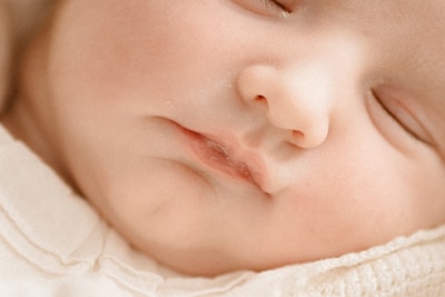 Close-up of a baby’s peaceful face, emphasizing natural textures and tones.